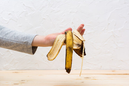 main qui tient des peaux de bananes